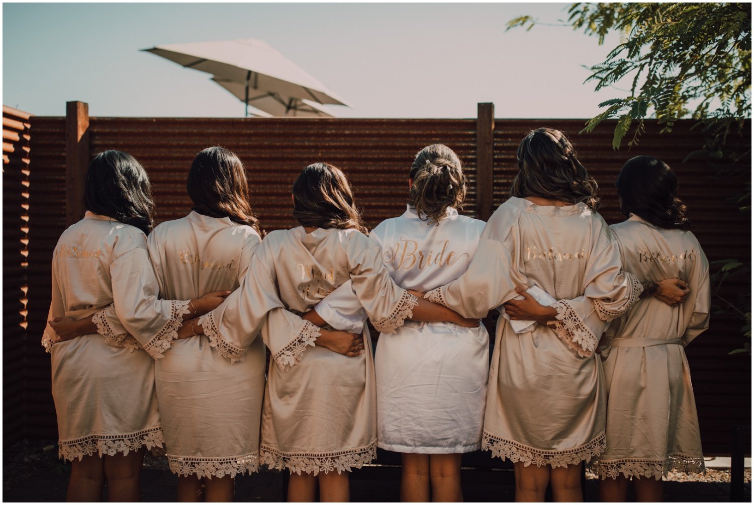 bridesmaids wearing emerald green dresses and champagne robes