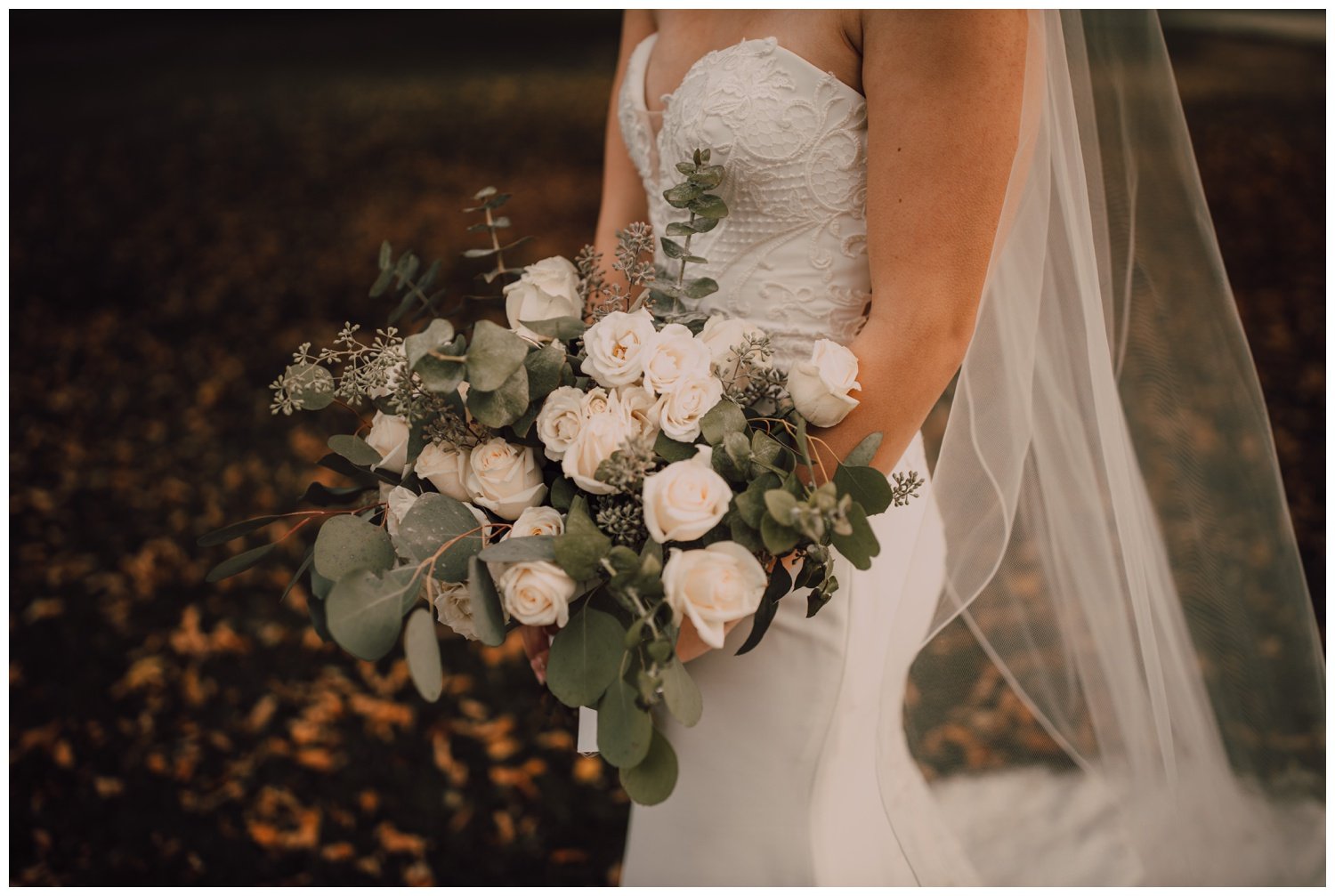 bride holding a bouquet of silver dollar eucalyptus and white roses