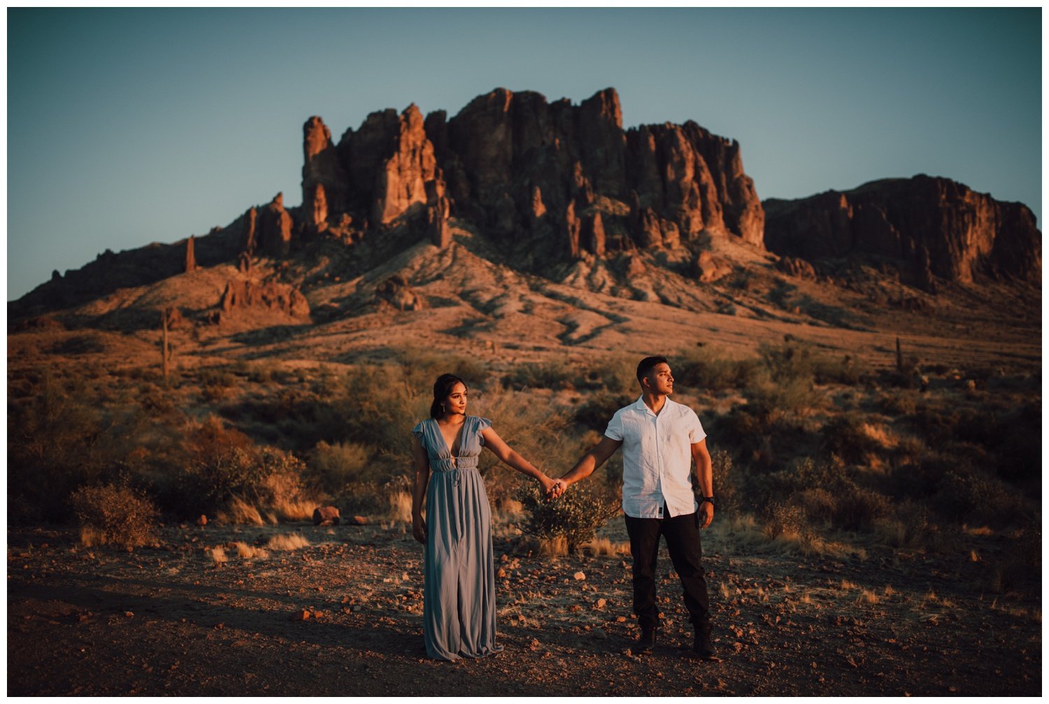 couple holding hands in front of the superstition mountains