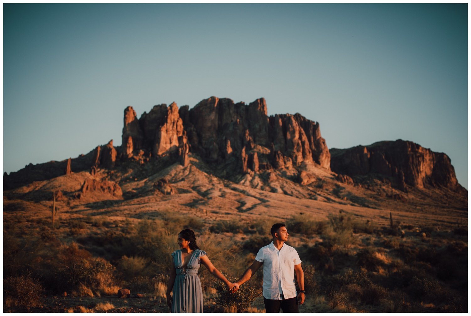 couple holding hands in front of the superstition mountains