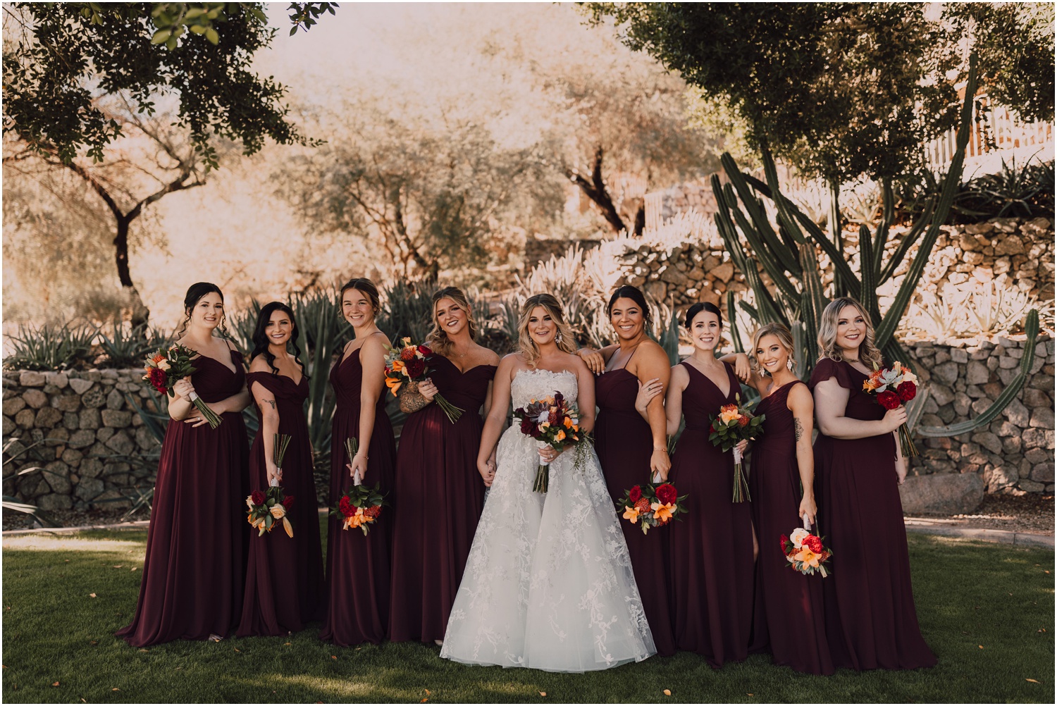 bride posing with her bridesmaids wearing burgundy dresses