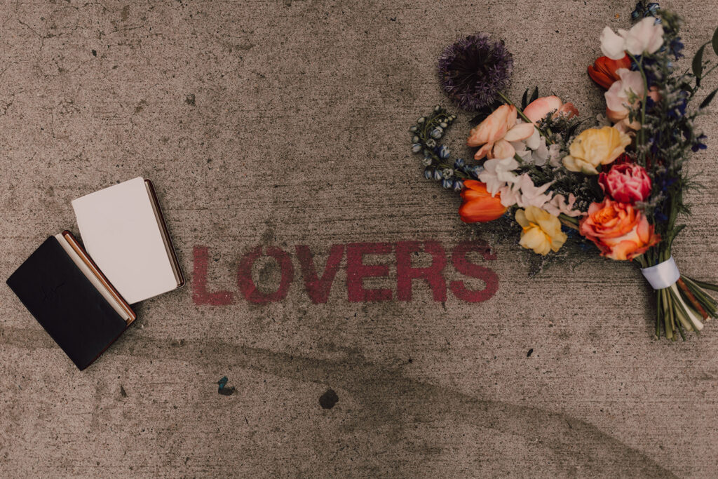 LOVERS written on the ground with bouquet and vows next to it 