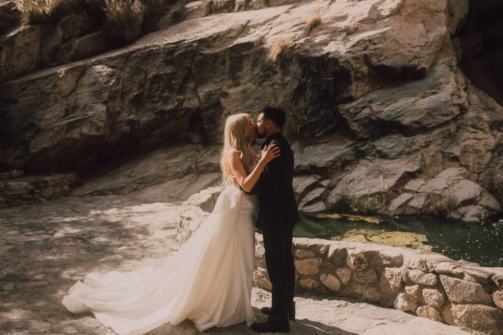 bride and groom kiss surrounded by a mountain 