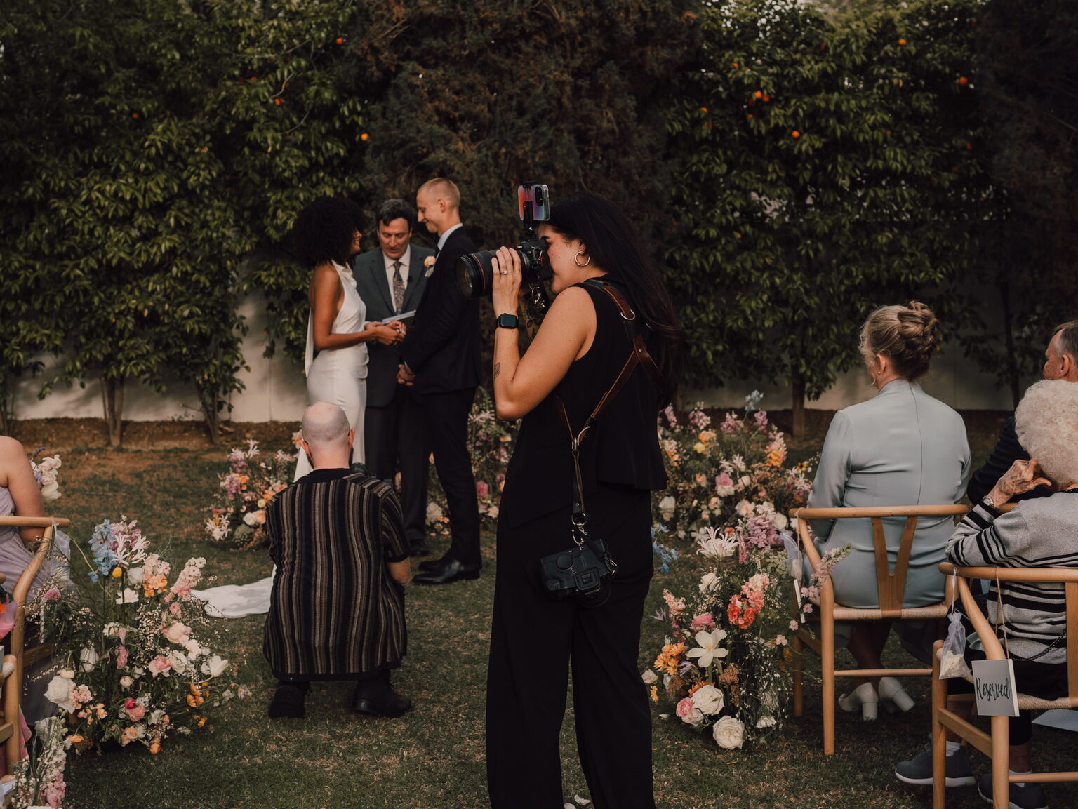 Photographer taking photo of outdoor wedding ceremony 