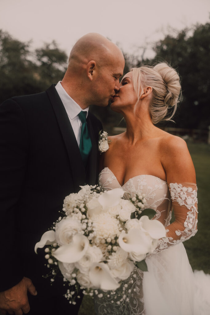 bride and groom kissing holding bouquet