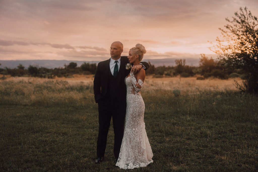 Bride and groom pose at sunset 