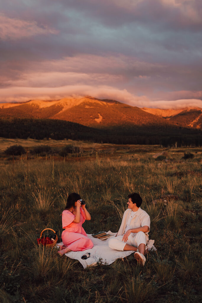 Sunset engagement session in a field with wine and props