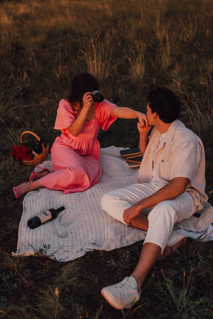 Sunset engagement session in a field with wine and props