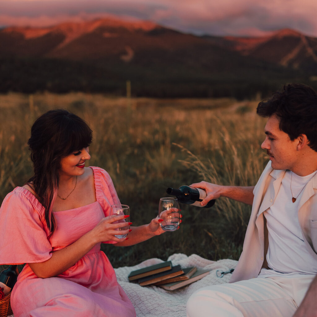 Sunset engagement session in a field with wine and props