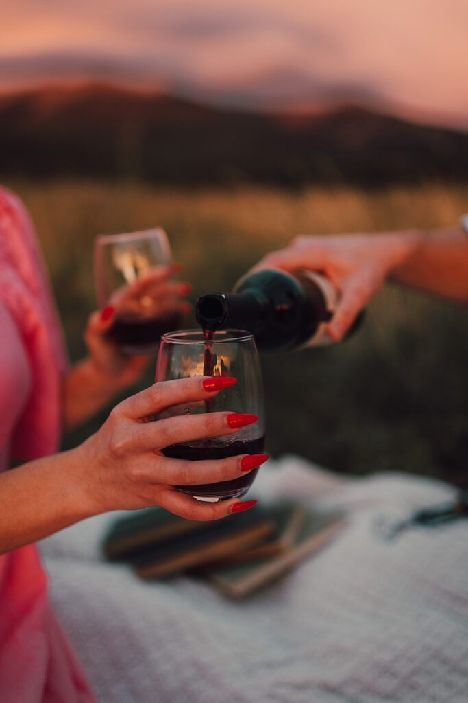 Sunset engagement session in a field with wine and props