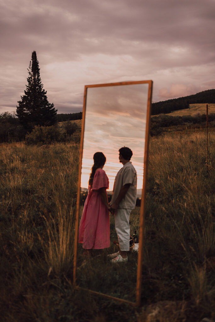 Sunset engagement session in a field with wine and props