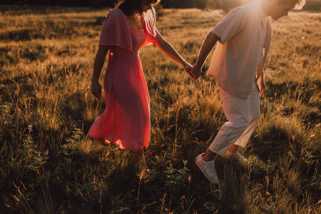 Sunset engagement session in a field with wine and props